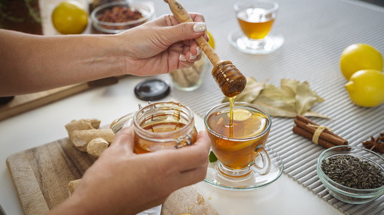 Person adding honey to a cup of tea