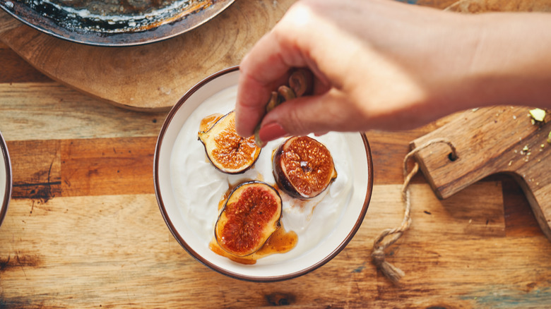 Hand dropping nuts onto fruit brûlée