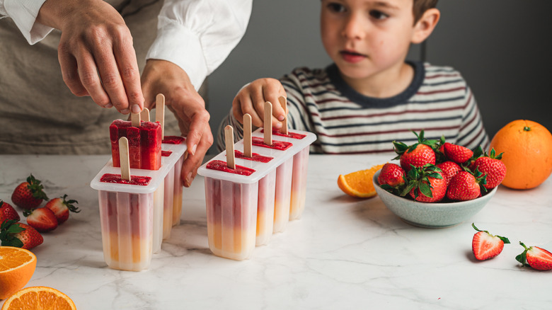 Woman and boy making fruit popsicles 