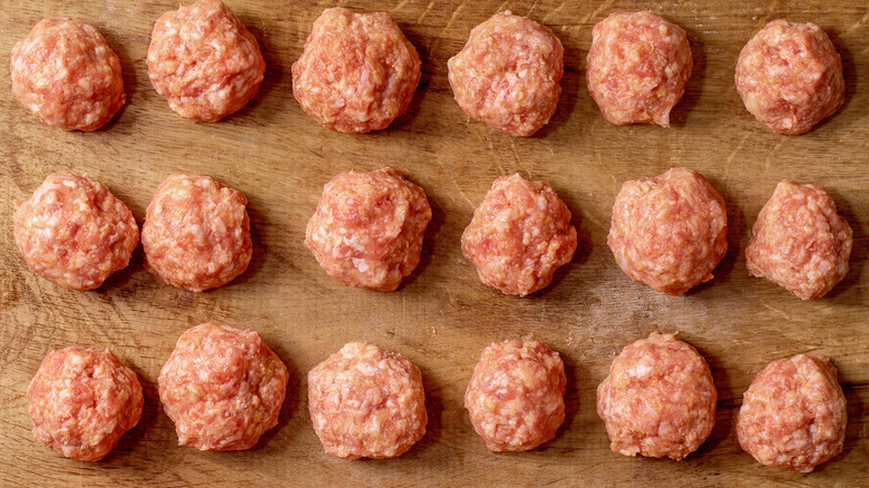 raw meatballs lined up on a wooden board