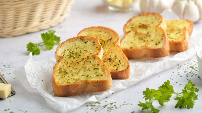 Slices of garlic bread on top of parchment paper