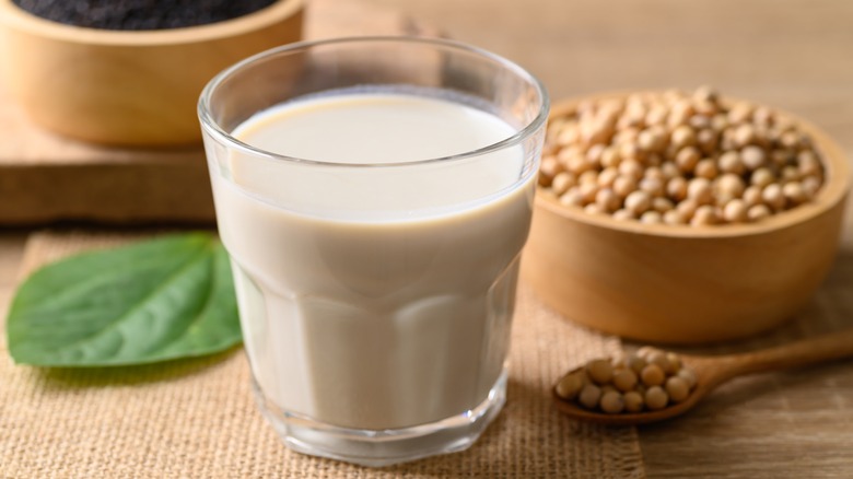 glass of soymilk next to soybeans