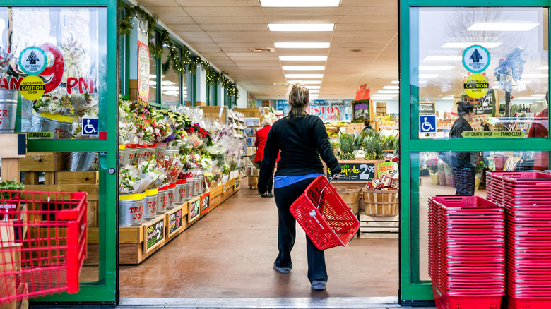 A female customer walks into a Trader Joe's grocery store holding a red basket