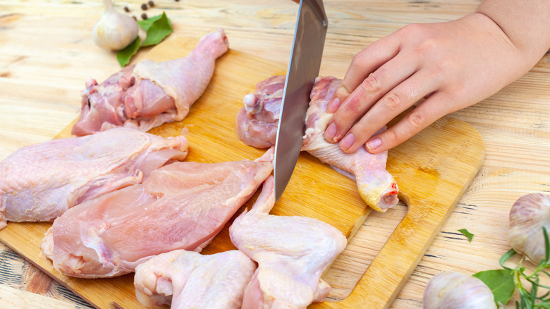 Person cutting up a whole chicken