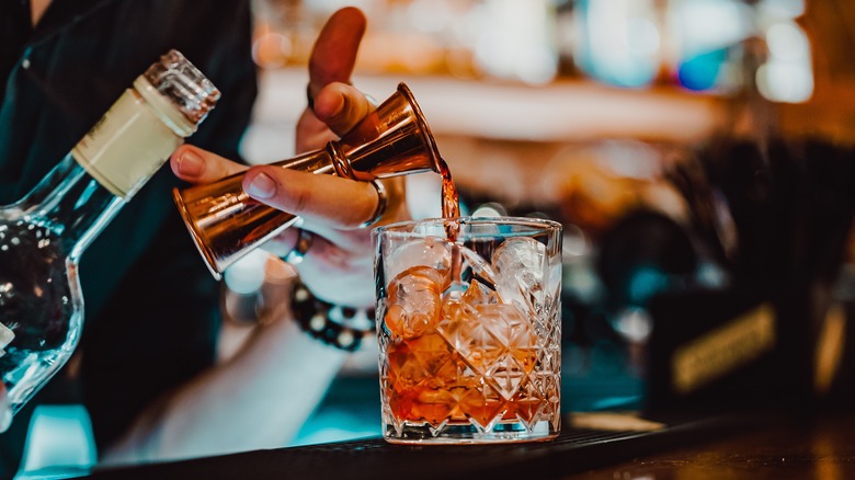 Bartender pouring a cocktail into a glass with ice