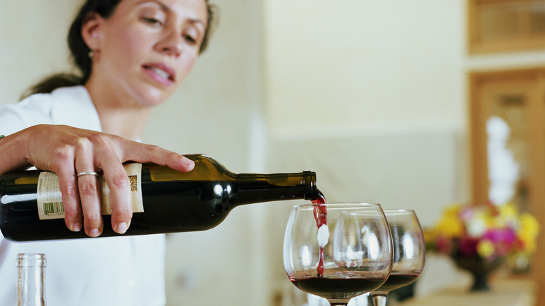 a woman bartender pouring red wine