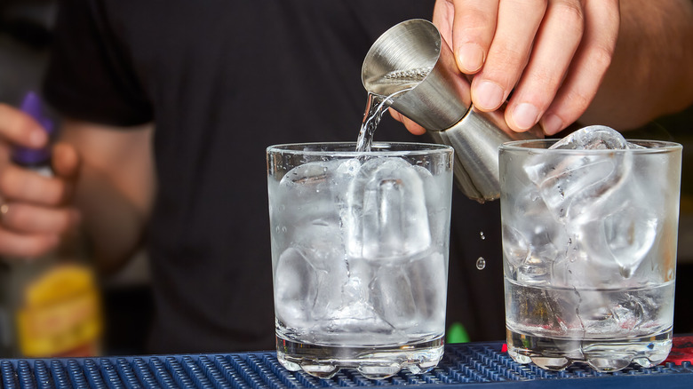 Vodka poured from measure into a glass of ice