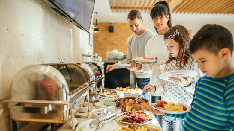 Family of 4 serves themselves food from a breakfast buffet