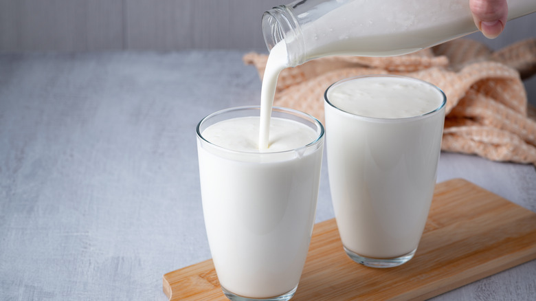 person pouring buttermilk into two glasses