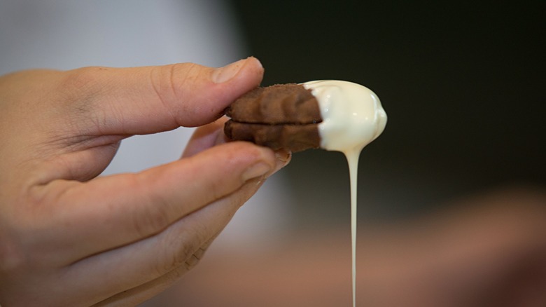 A cookie being dipped in white chocolate