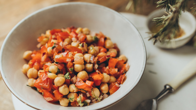 Chickpeas with dressing and diced vegetables in a white bowl