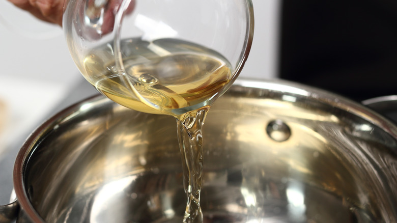 Pouring glass of white wine into pan to make wine reduction sauce