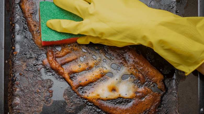 Person scrubbing greasy sheet pan
