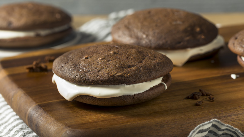 Homemade chocolate moon pies sit on top of a wooden cutting board