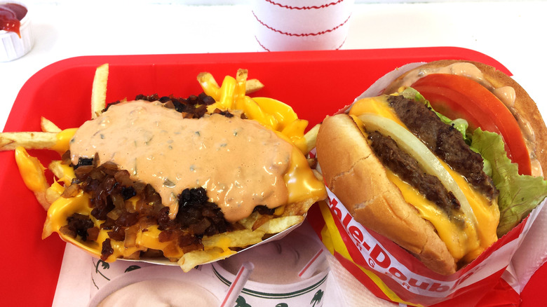 In'n'Out tray is full of animal-style fries with melted cheese, grilled onions, and spread, next to a double double cheeseburger