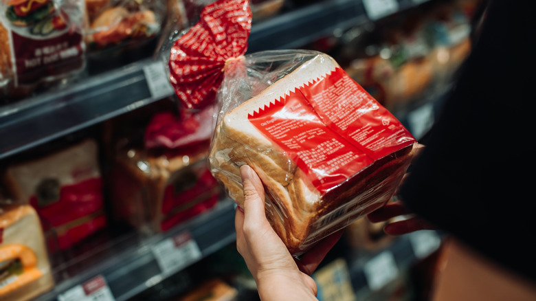 A shopper looks at the nutrition facts on the back of a package of bread