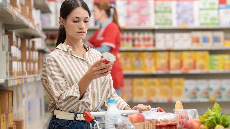 A shopper looks at the nutrition facts on a can of food