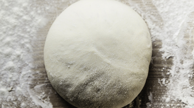 pizza dough on a floured wooden surface