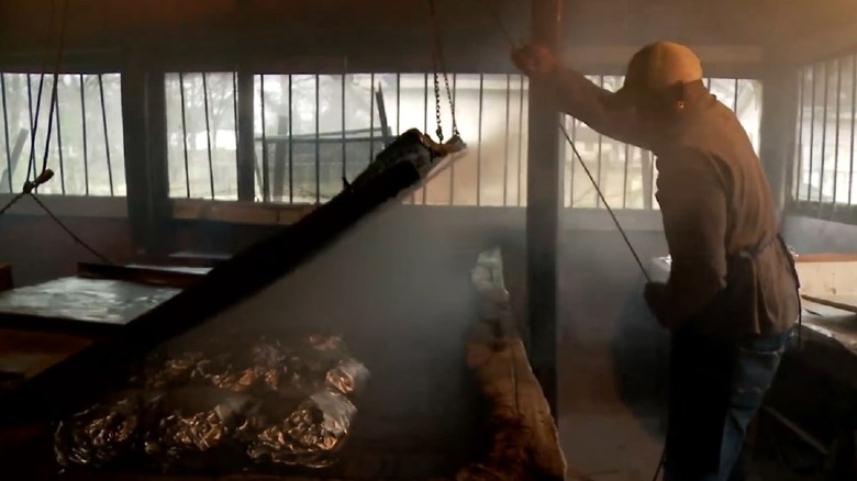 A Jones pitmaster checks on a batch of pork shoulders