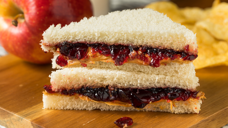 Crustless peanut butter and jelly sandwich triangles with a red apple in the background