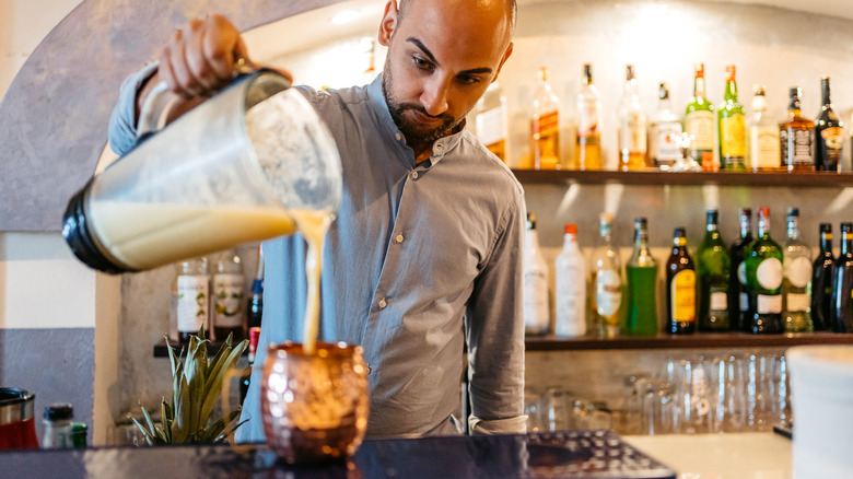 bartender pouring blended cocktail from blender