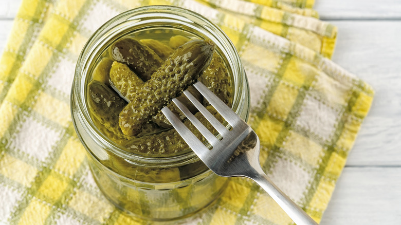 Pickled cornichons in a jar with a fork