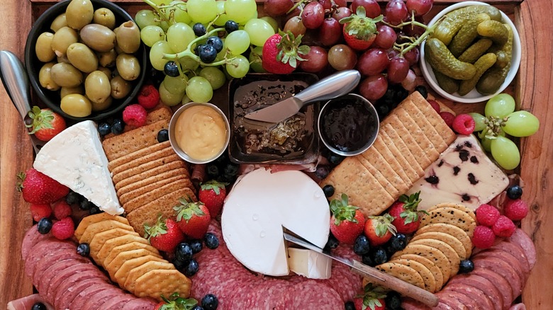 Charcuterie board with meats, cheeses, fruit, and pickles