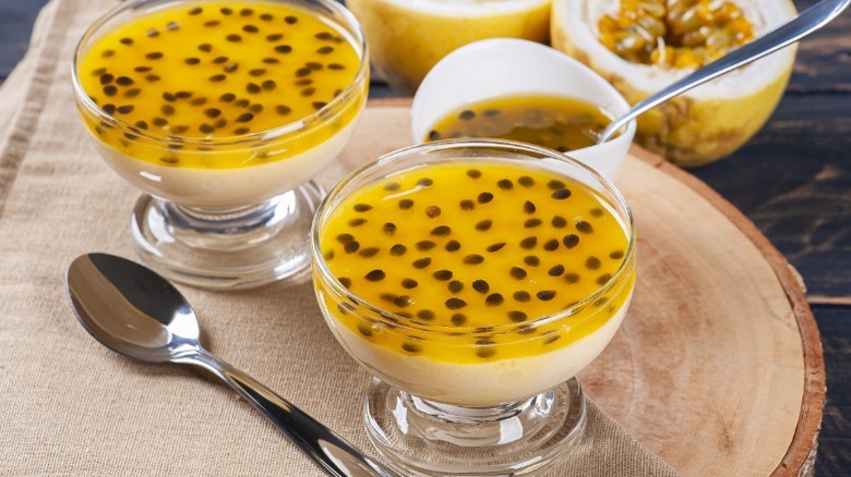 Two bowls of passion fruit mousse on a wooden tray 