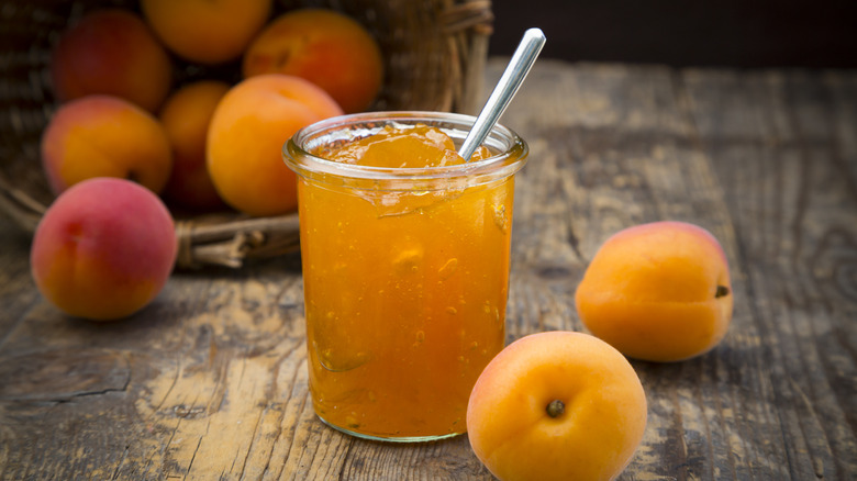 Jar of apricot jam next to fresh apricots