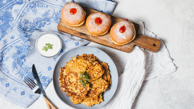 Table with Jewish Hanukkah foods of potato latkes and jelly-filled sufganiyot.