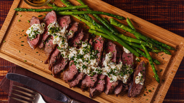 Sliced steak with blue cheese butter garnish and asparagus