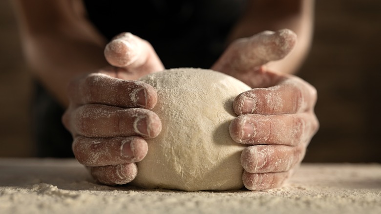 Hands knead pasta dough