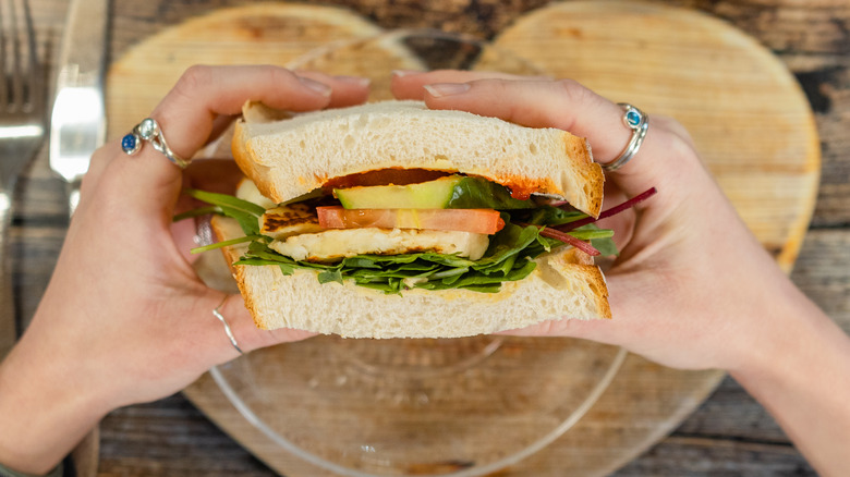 Person eating a sandwich above a heart-shaped placemat