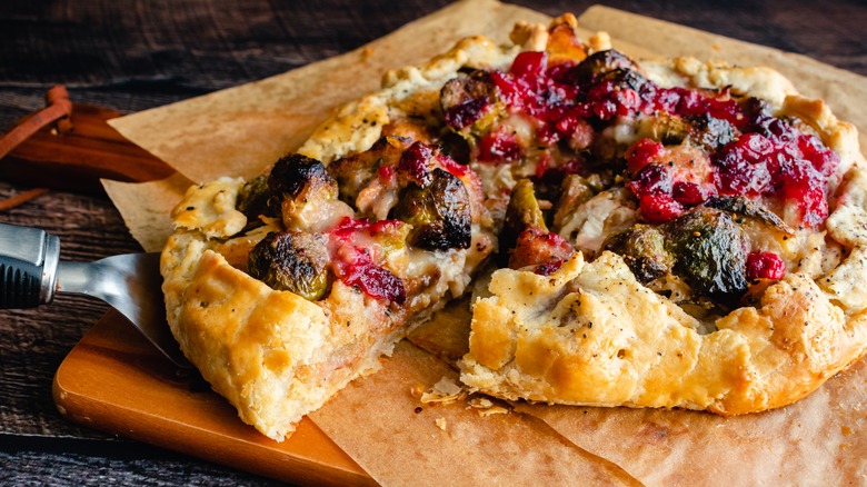 A flatbread full of Thanksgiving leftovers including brussel sprouts, cranberry sauce, and turkey