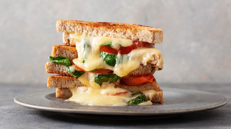 Stacked grilled cheese sandwich with tomato and basil