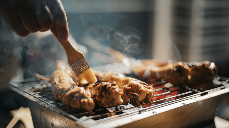 Chicken on a grill being basted with marinade