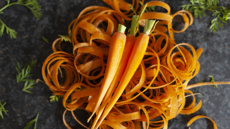 Whole carrots and their peels on a black background