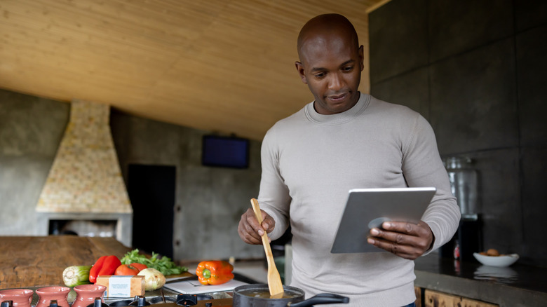 Man cooking along with recipe on tablet