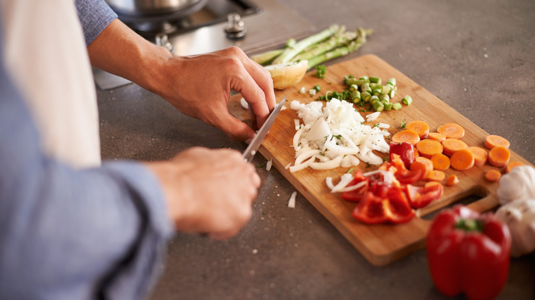 Person slicing vegetables on cutting board