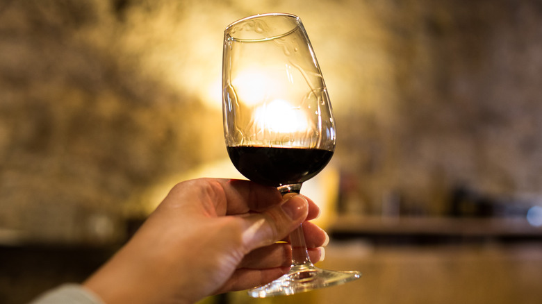 Person's hand holding a glass of port