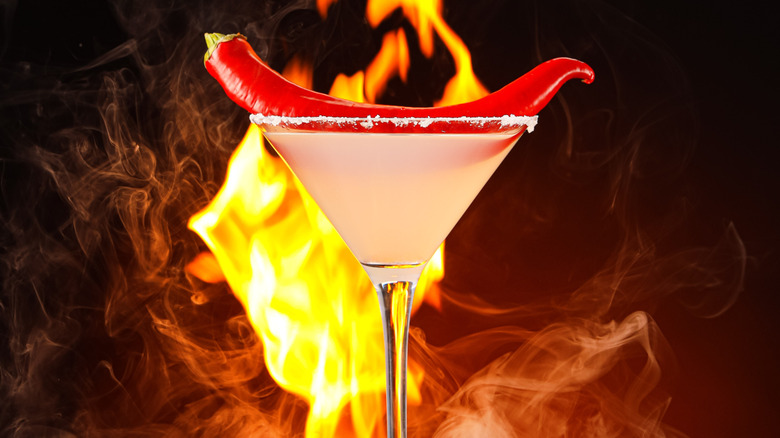 Margarita with a pepper on top and a flame against dark background