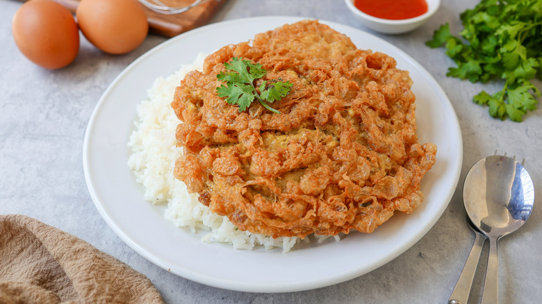 A Thai-style omelet (Kai jeow moo sab) is on a plate with rice.