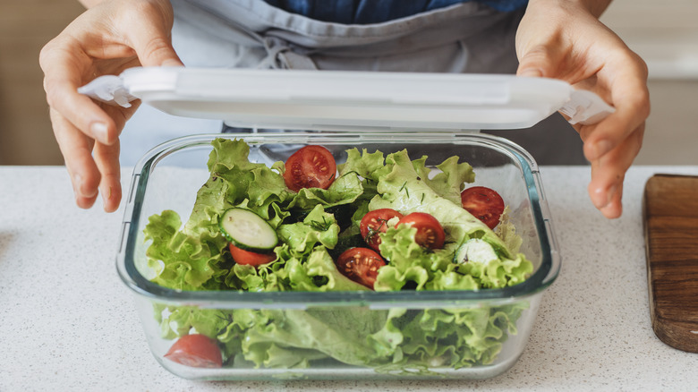 Hands placing lid on salad container