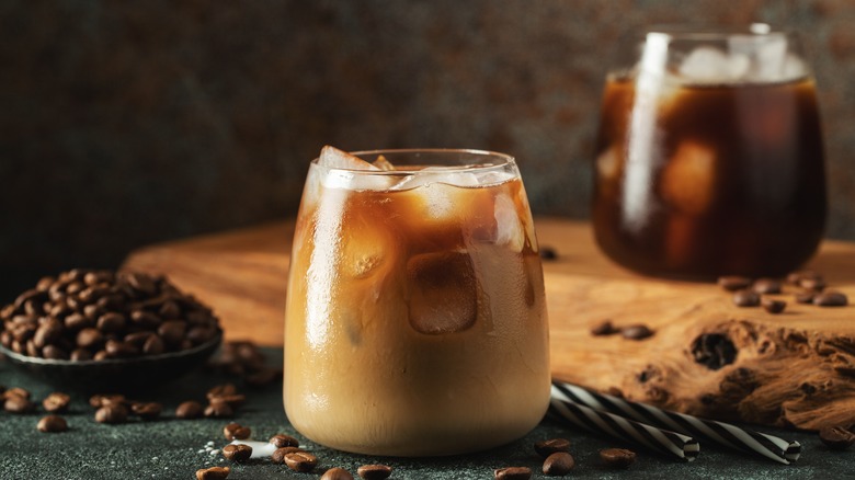 Two glasses of iced coffee with coffee beans around them