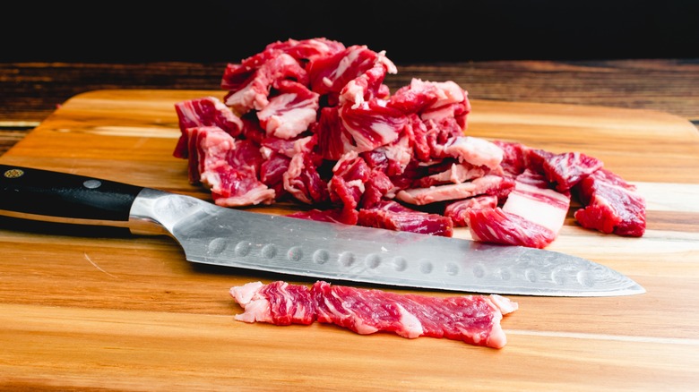 Thinly sliced strips of steak on board with knife