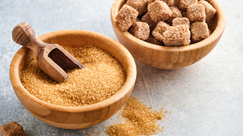 Brown sugar crystals and cubes in wooden bowls