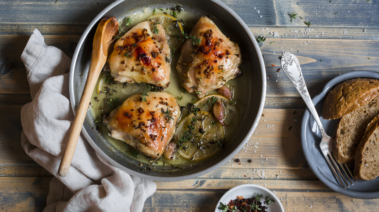 Cooked chicken thighs in skillet with wine and herbs