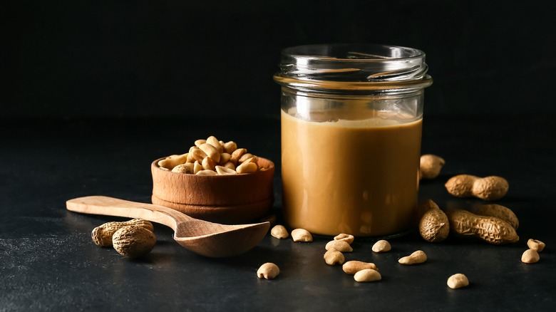 Glass jar of peanut butter with peanuts