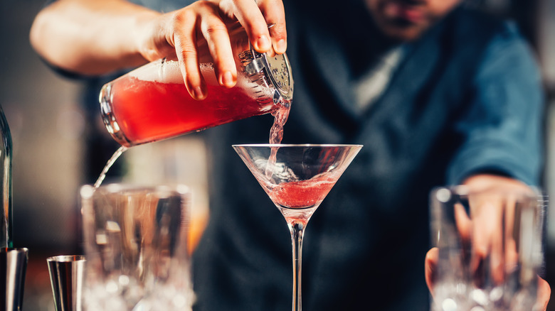 Bartender pouring cosmo into martini glass