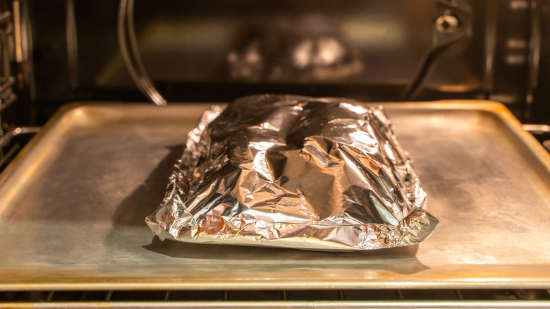 Meat wrapped in aluminum foil in the oven.